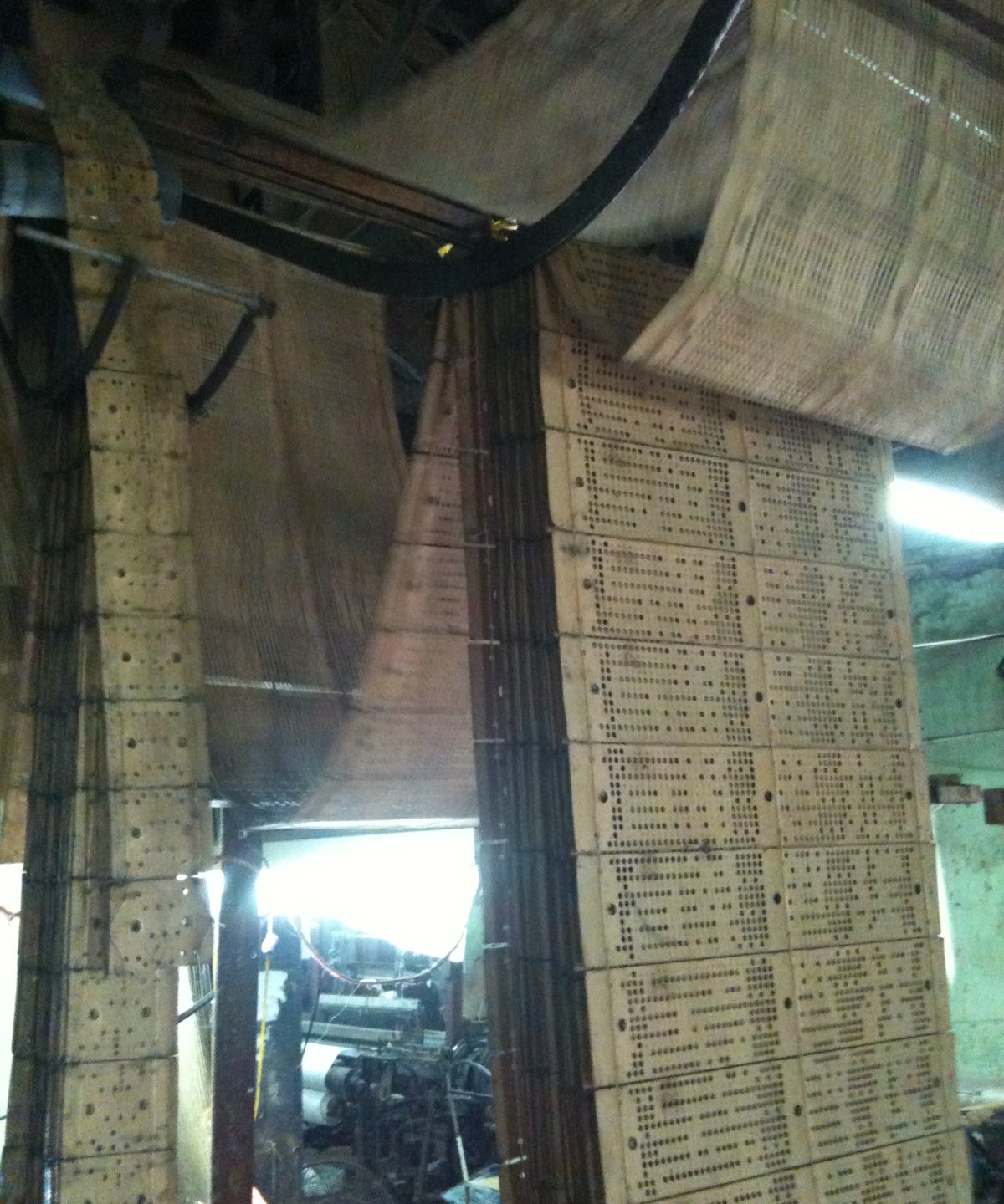 Chains of punched pattern cards hanging beside a loom